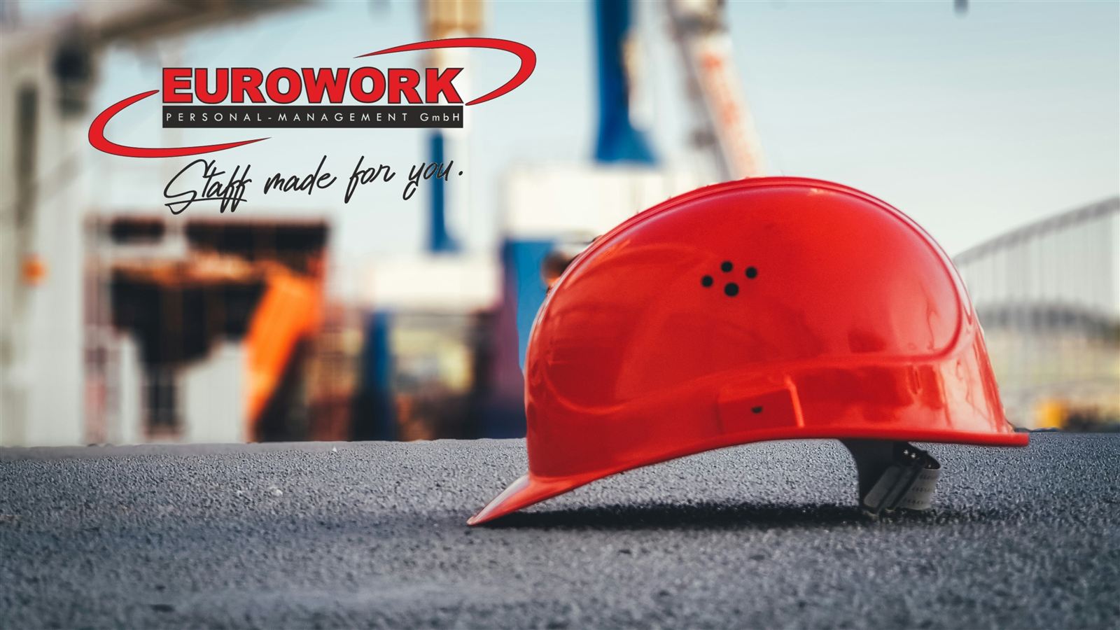 Roter Schutzhelm auf einer Baustelle mit Eurowork-Logo – Staff made for you.